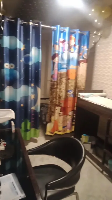 A child-friendly consultation room at Nulife Children's Clinic, with brightly patterned curtains and an examination table.